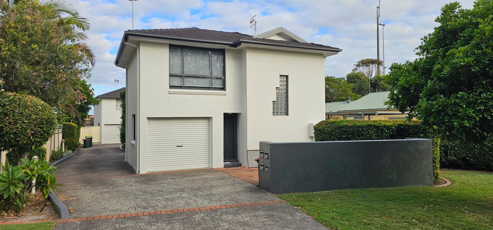 Two storey rendered home repainted in off white with a light garage door