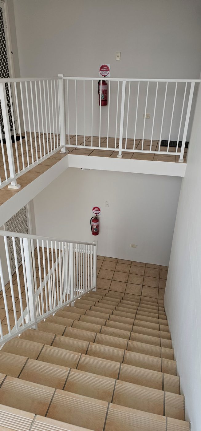 Looking down a freshly painted stairwell with white walls and railings