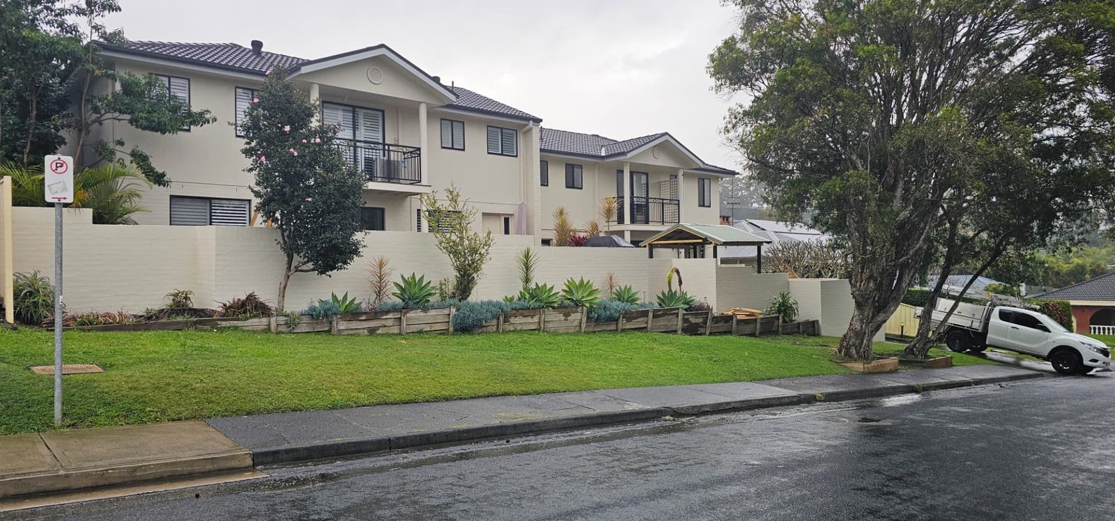 Street view of a townhouse complex with a newly painted front boundary wall