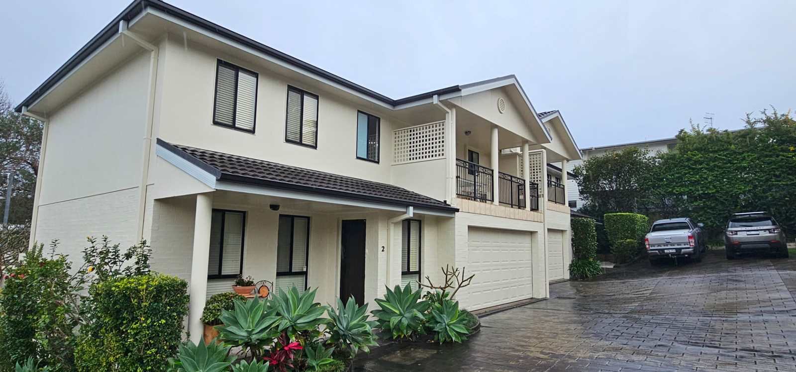 Repainted cream townhouse with dark window frames and a tiled porch roof